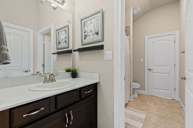 Full bath featuring vanity, toilet, tile patterned floors, vaulted ceiling, and curtained shower | Image 31