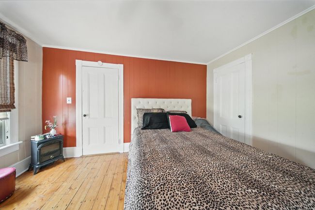 Bedroom featuring light wood-type flooring, crown molding, and a wood stove | Image 26