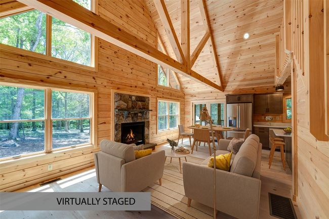 Unfurnished living room with wooden walls, wooden ceiling with exposed beams, plenty of natural light, hardwood / wood-style flooring, and a fireplace | Image 8