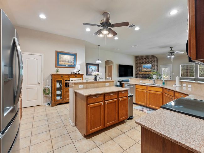 Kitchen featuring stainless steel refrigerator with ice dispenser, a ceiling fan, arched walkways, a sink, and recessed lighting | Image 9