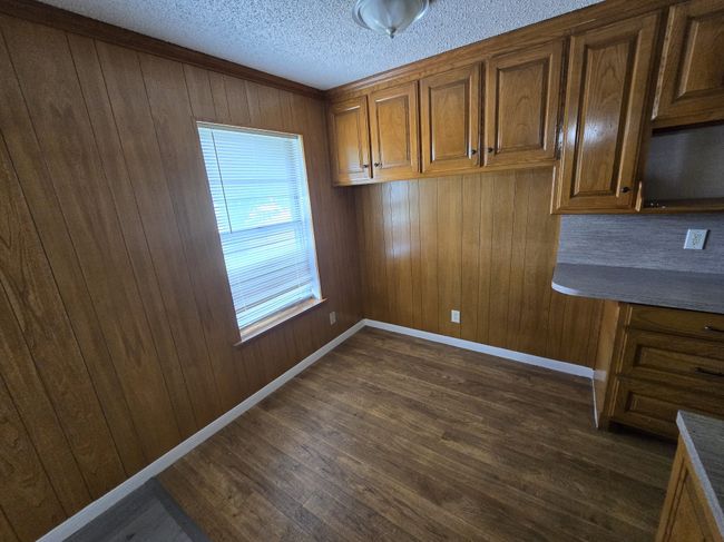 Unfurnished dining area with dark wood-style floors, wood walls, and a textured ceiling | Image 17