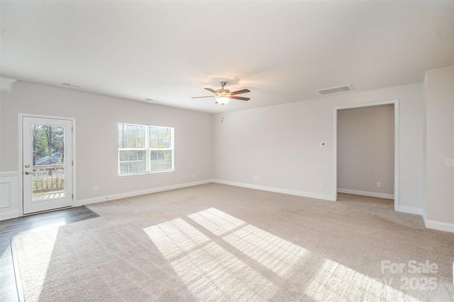 Open Family Room showing door out to the Deck and entryway to the Primary Bedroom on the right and the entryway to the Laundry/Mud Room and Garage Entry to the left. | Image 12