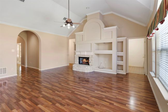 Unfurnished living room with arched walkways, healthy amount of natural light, dark wood finished floors, a ceiling fan, and high vaulted ceiling | Image 22