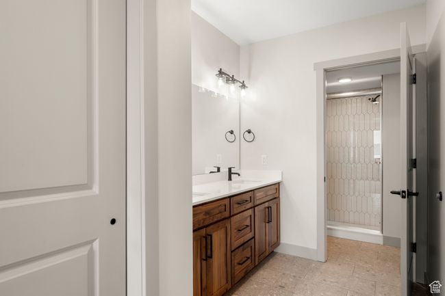 Bathroom featuring a stall shower, double vanity, baseboards, and tile patterned flooring | Image 15