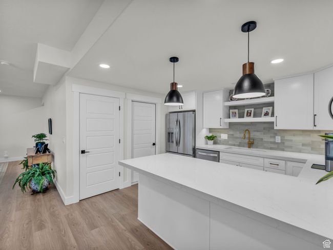 Kitchen featuring stainless steel appliances, a sink, light countertops, open shelves, and white cabinetry | Image 36