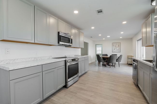 Kitchen featuring appliances with stainless steel finishes, gray cabinets, light wood-style floors, recessed lighting, and light countertops | Image 14