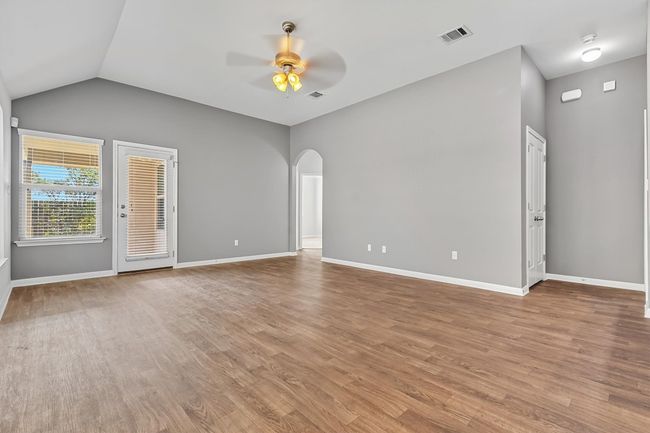 Unfurnished living room featuring arched walkways, light wood-style flooring, ceiling fan, and vaulted ceiling | Image 13