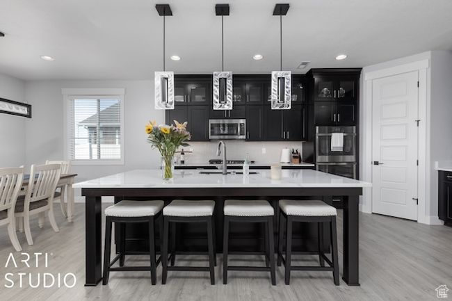 Kitchen featuring dark cabinetry, a sink, stainless steel appliances, light countertops, and a kitchen breakfast bar | Image 10