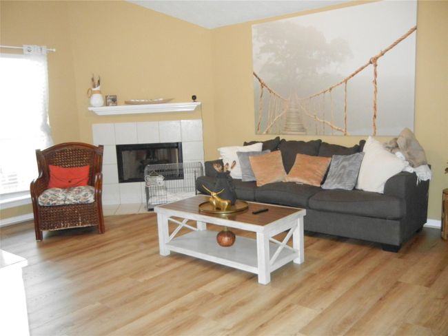 Living room with high ceiling, gas log fireplace, Dura-Shield commercial vinyl plank flooring, and cordless blinds throughout. | Image 16