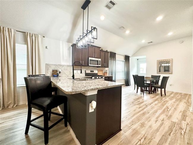 Elegant eat-in kitchen with abundant natural light, upgraded lighting and sink, and lots of counter space and cabinets for storage. | Image 6