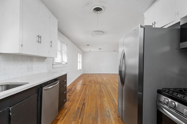 Kitchen with stainless steel appliances, light countertops, backsplash, and white cabinetry | Image 29