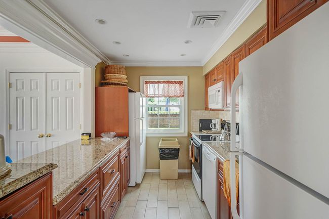 Kitchen featuring white appliances, tasteful backsplash, crown molding, light stone countertops, and recessed lighting | Image 30