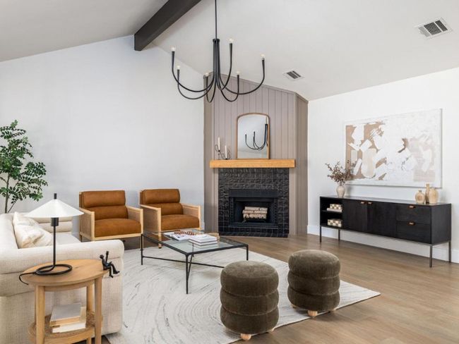 Living area featuring lofted ceiling with beams, visible vents, a tiled fireplace, and light wood-type flooring | Image 9