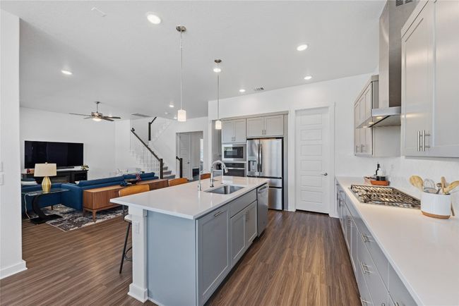 Kitchen featuring a sink, stainless steel appliances, gray cabinetry, and wall chimney exhaust hood | Image 6