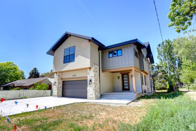 View of front facade featuring a garage, stone siding, concrete driveway, stucco siding, and board and batten siding | Image 40