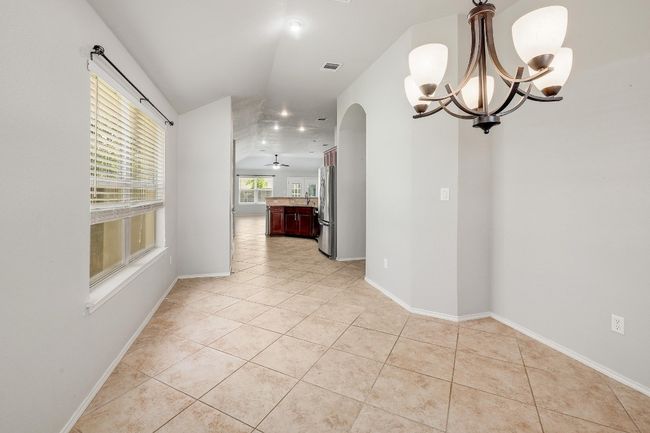 Spare room featuring a chandelier, light tile patterned floors, and arched walkways | Image 8
