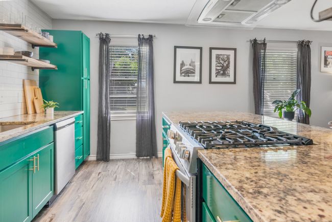 Kitchen featuring appliances with stainless steel finishes, open shelves, light wood-type flooring, light stone countertops, and green cabinets | Image 13