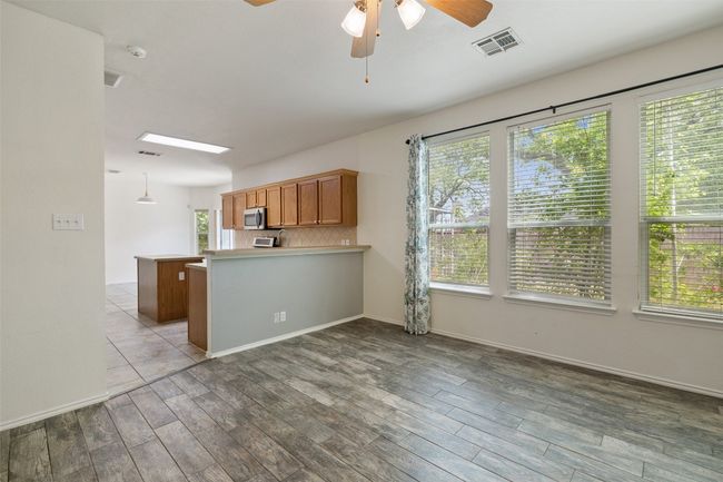 Kitchen featuring ceiling fan, light countertops, a peninsula, stainless steel microwave, and visible vents | Image 19