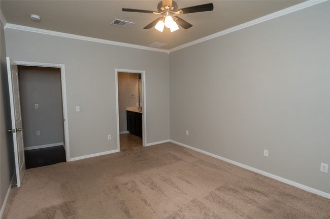 Unfurnished bedroom featuring crown molding, carpet flooring, baseboards, connected bathroom, and a ceiling fan | Image 13