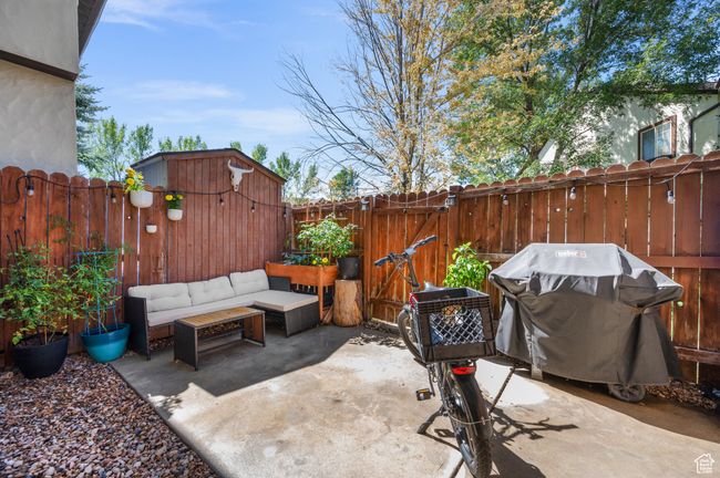 Fenced backyard with a grill, a patio area, a gate, an outdoor living space, and a shed | Image 13