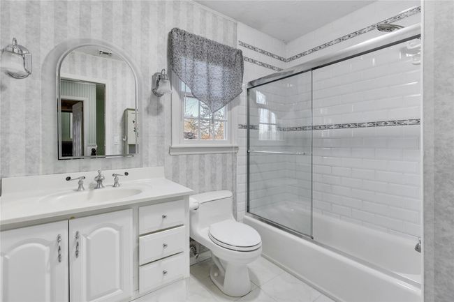 Full bathroom featuring wallpapered walls, toilet, vanity, and shower / bath combination with glass door | Image 19
