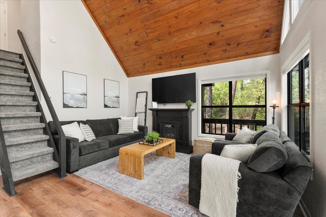 Living area featuring stairway, wood finished floors, wood ceiling, a glass covered fireplace, and high vaulted ceiling | Image 17