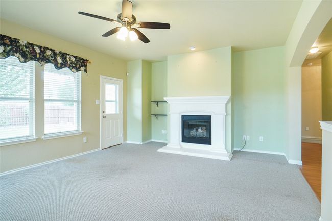Unfurnished living room featuring carpet flooring, a ceiling fan, a glass covered fireplace, and baseboards | Image 12