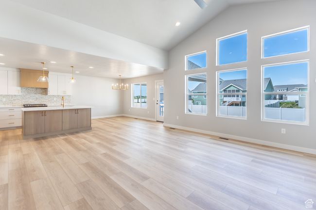 Unfurnished living room featuring a sink, a chandelier, light wood finished floors, baseboards, and recessed lighting | Image 7