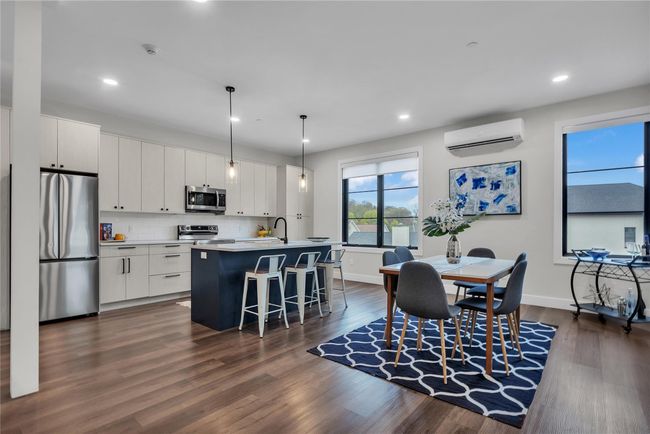 Kitchen featuring appliances with stainless steel finishes, a wall mounted AC, a breakfast bar area, dark wood-type flooring, and recessed lighting | Image 8