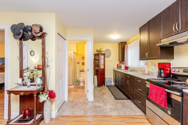 Kitchen featuring stainless steel electric range, under cabinet range hood, dark brown cabinetry, light countertops, and white microwave | Image 24