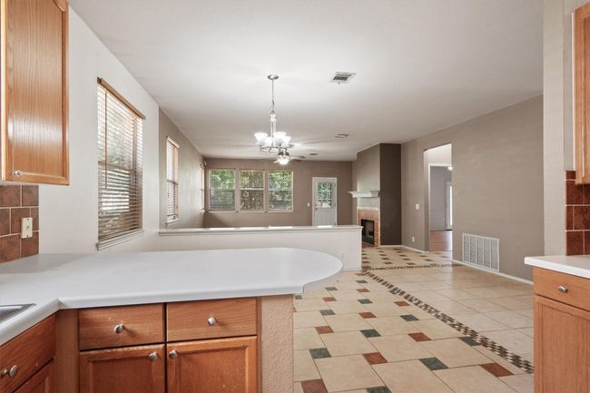 Kitchen with a peninsula, light tile patterned floors, a chandelier, light countertops, and open floor plan | Image 19