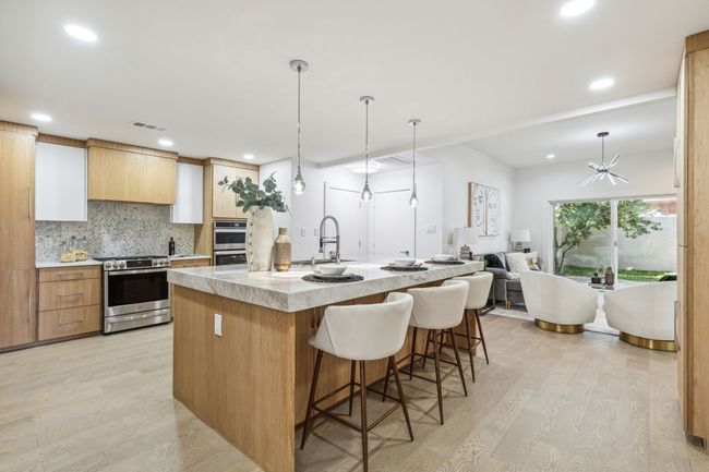 Kitchen with light countertops, light wood-type flooring, decorative backsplash, appliances with stainless steel finishes, and a sink | Image 13