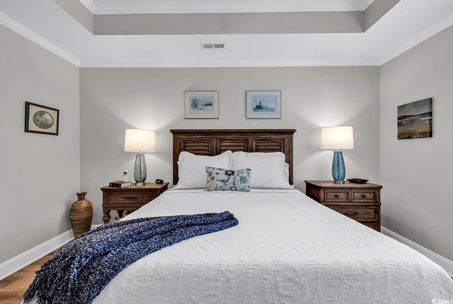 Bedroom featuring a raised ceiling, light wood-type flooring, and crown molding | Image 14