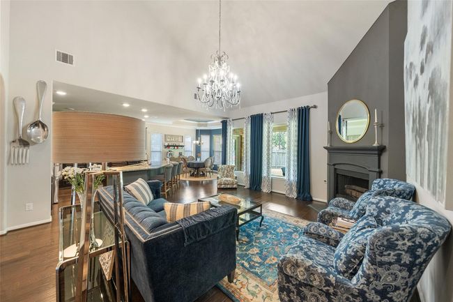 Another angle of the living area features an open layout with high ceilings and ample natural light. It includes a decorative fireplace, and a stylish chandelier. | Image 13