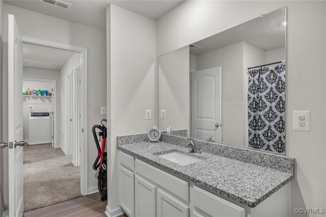 Full bathroom featuring visible vents, baseboards, wood finished floors, vanity, and washer / dryer | Image 20