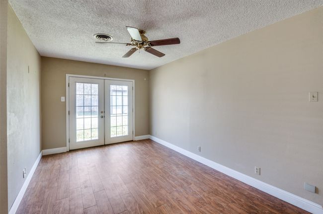 Empty room with ceiling fan, a textured ceiling, light wood-type flooring, and french doors | Image 7