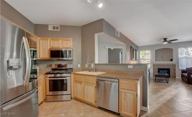 Kitchen featuring light brown cabinets, stainless steel appliances, a sink, a peninsula, and open floor plan | Image 10