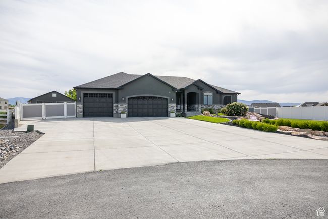 View of front facade with an attached garage, driveway, stucco siding, and stone siding | Image 4
