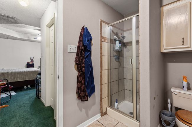 Ensuite bathroom with a textured ceiling, toilet, a stall shower, ensuite bathroom, and visible vents | Image 20