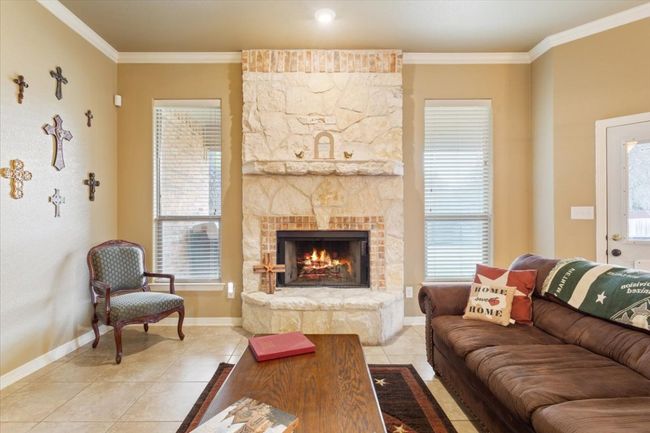 Living area featuring baseboards, a fireplace, ornamental molding, and light tile patterned flooring | Image 12