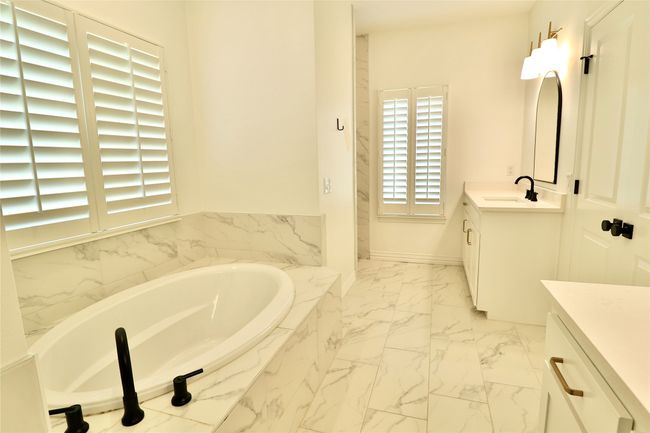 Full bath with a garden tub, marble finish floor, and vanity | Image 15