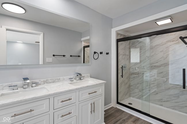 bathroom with double vanity, a marble finish shower, and wood finished floors | Image 20
