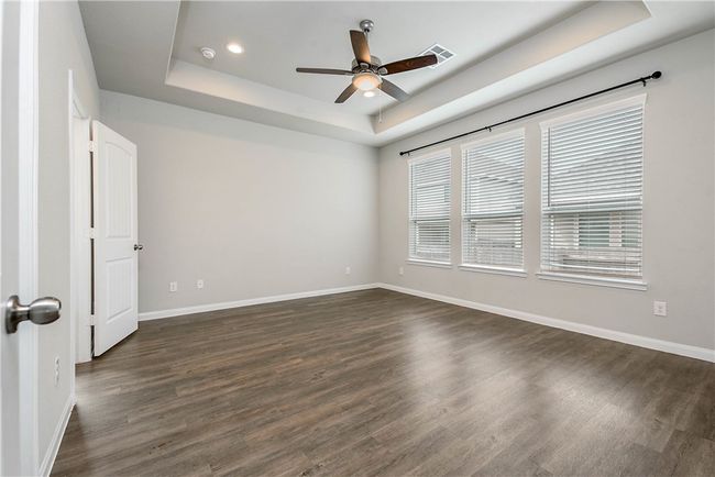 Spare room featuring a raised ceiling, ceiling fan, dark wood-type flooring, and recessed lighting | Image 11