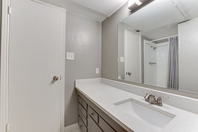 Bathroom with visible vents, a textured wall, vanity, and a shower with curtain | Image 19