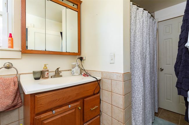 Bathroom with tile patterned flooring, vanity, tile walls, and a shower with shower curtain | Image 15