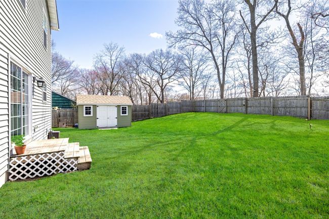 View of yard featuring a fenced backyard, a storage unit, an outdoor structure, and a deck | Image 27