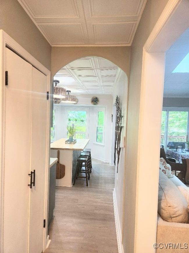 Hallway featuring an ornate ceiling, arched walkways, wood finished floors, and healthy amount of natural light | Image 5