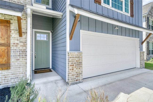 Property entrance with a garage, board and batten siding, and brick siding | Image 4