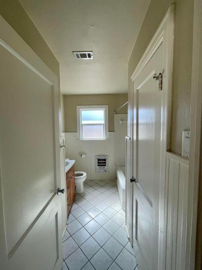 Bathroom featuring vanity, toilet, wainscoting, shower combination, and heating unit | Image 13