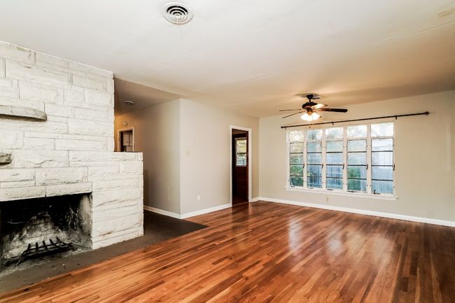 Unfurnished living room featuring a ceiling fan, wood finished floors, and plenty of natural light | Image 6